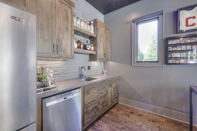 kitchen with stone counters, appliances with stainless steel finishes, sink, and dark hardwood / wood-style flooring