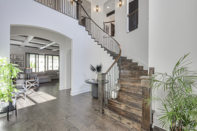 stairs featuring coffered ceiling, hardwood / wood-style flooring, and a high ceiling