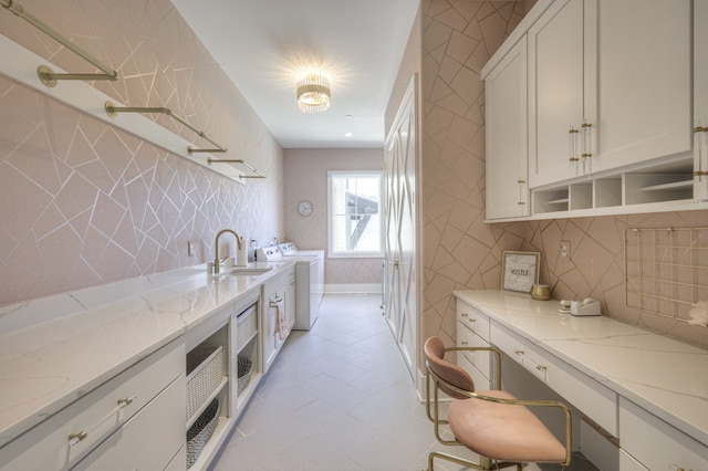 kitchen with white cabinets, tasteful backsplash, light stone countertops, independent washer and dryer, and sink