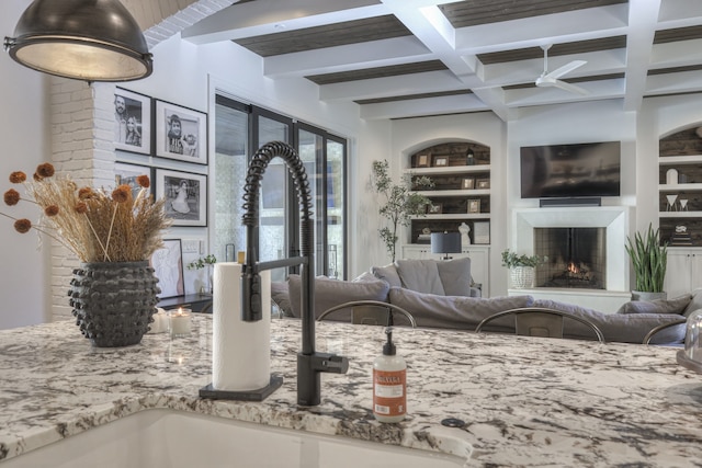 interior space with ceiling fan, beamed ceiling, built in shelves, sink, and coffered ceiling