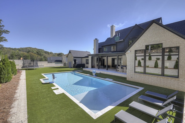 view of swimming pool featuring a patio, a trampoline, and a yard