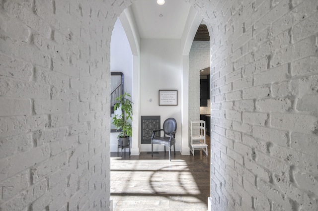 hallway with brick wall and hardwood / wood-style flooring