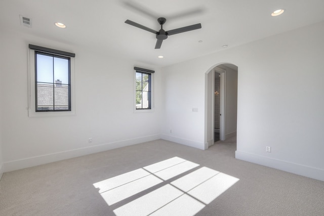 spare room featuring light colored carpet, a healthy amount of sunlight, and ceiling fan