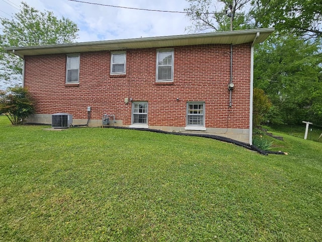 rear view of property with central AC and a yard