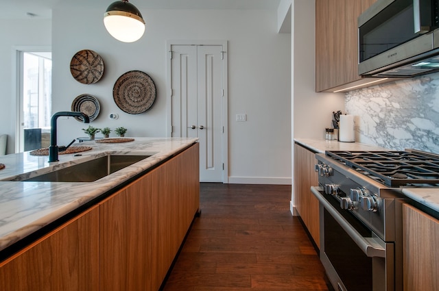 kitchen with light stone countertops, sink, backsplash, dark hardwood / wood-style flooring, and stainless steel appliances