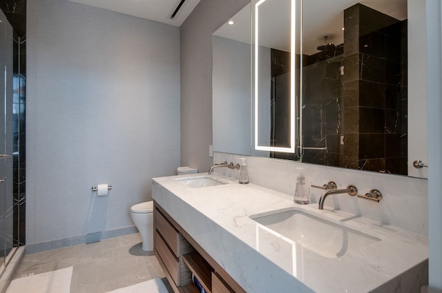 bathroom with vanity, toilet, tile patterned floors, and tiled shower