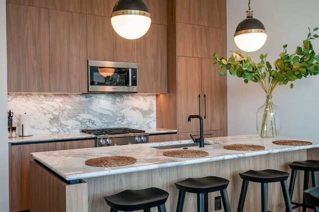 kitchen featuring light stone countertops, sink, hanging light fixtures, stainless steel appliances, and decorative backsplash