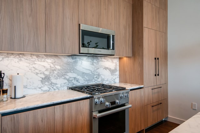 kitchen with decorative backsplash, dark hardwood / wood-style flooring, appliances with stainless steel finishes, light stone countertops, and light brown cabinetry