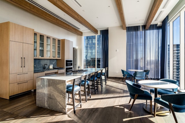 kitchen featuring a kitchen island, beam ceiling, backsplash, light brown cabinetry, and dark hardwood / wood-style flooring