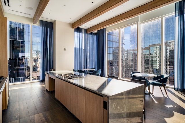 kitchen featuring beam ceiling, dark hardwood / wood-style flooring, a kitchen island, floor to ceiling windows, and stainless steel gas cooktop