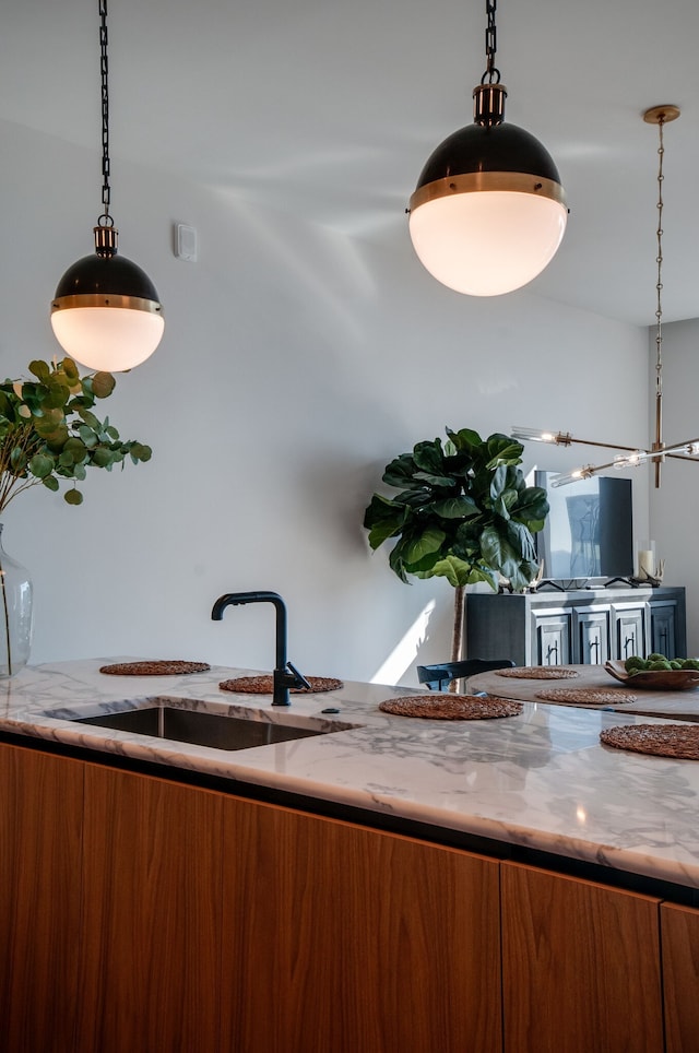 interior space with light stone countertops, a chandelier, sink, and hanging light fixtures