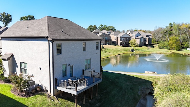 rear view of property with a lawn and a water view