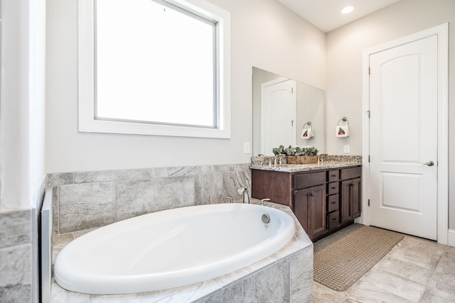 bathroom featuring tiled bath and vanity