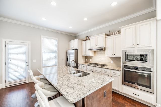 kitchen featuring a kitchen island with sink, white cabinets, sink, appliances with stainless steel finishes, and dark hardwood / wood-style flooring