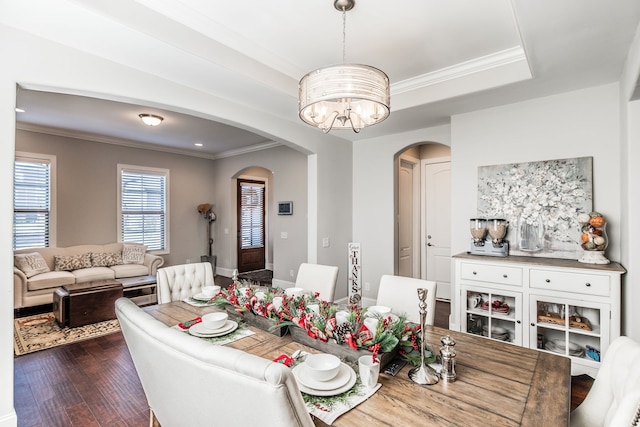 dining area featuring a raised ceiling, crown molding, dark hardwood / wood-style flooring, and an inviting chandelier