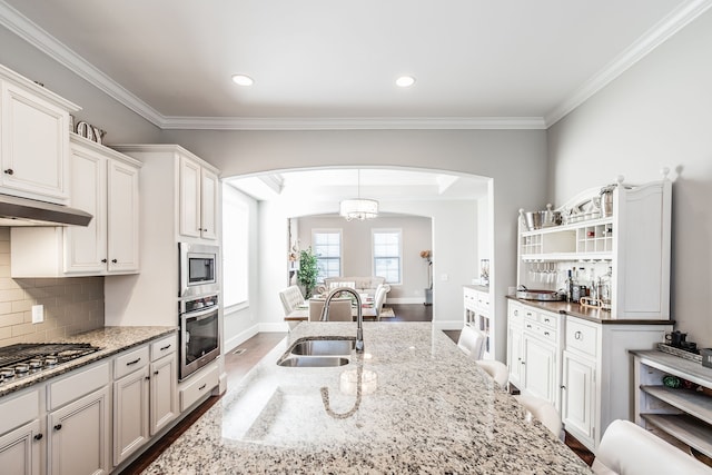 kitchen with sink, stainless steel appliances, light stone counters, dark hardwood / wood-style flooring, and white cabinets