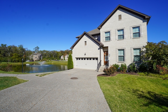 view of front of property featuring a front yard, a water view, and a garage