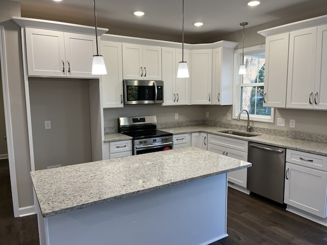 kitchen featuring pendant lighting, stainless steel appliances, white cabinetry, and sink