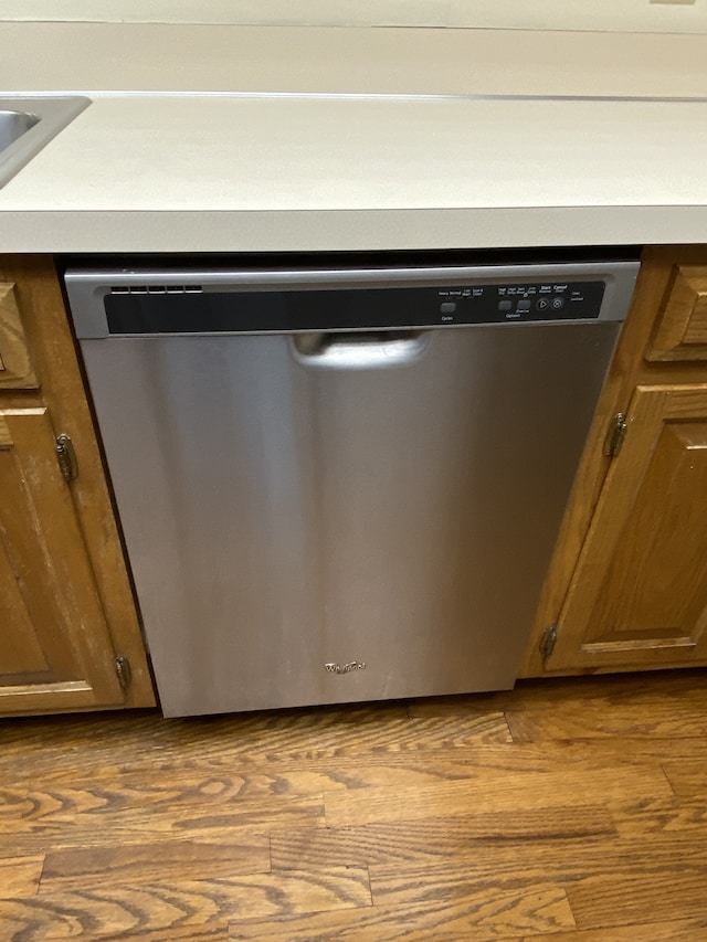 details with stainless steel dishwasher and hardwood / wood-style flooring