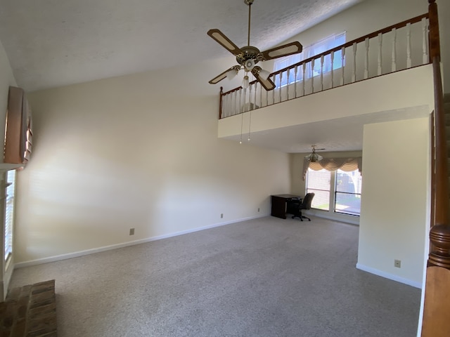 unfurnished living room featuring carpet, a high ceiling, and ceiling fan