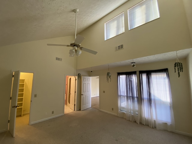 spare room featuring ceiling fan, high vaulted ceiling, light colored carpet, and a textured ceiling