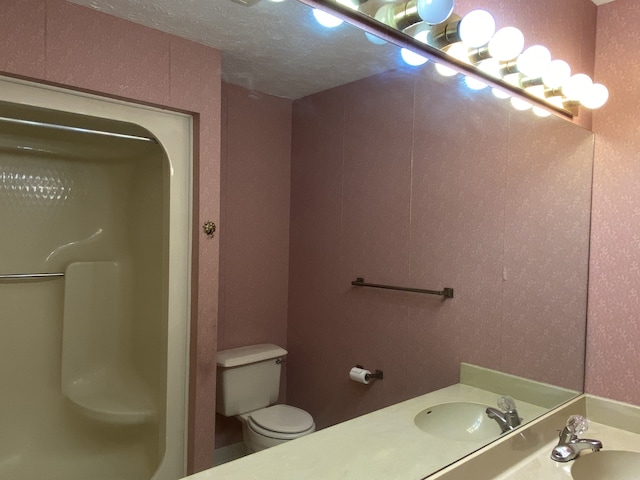 bathroom featuring a shower, vanity, a textured ceiling, and toilet