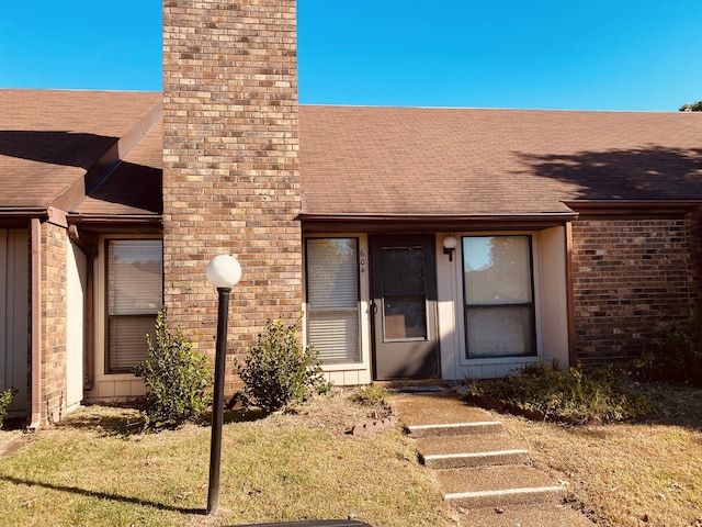 view of exterior entry featuring a lawn