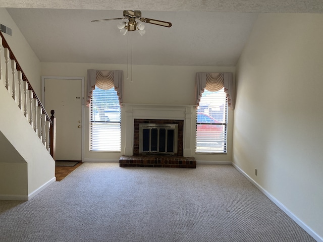 unfurnished living room with a textured ceiling, ceiling fan, a fireplace, carpet floors, and lofted ceiling