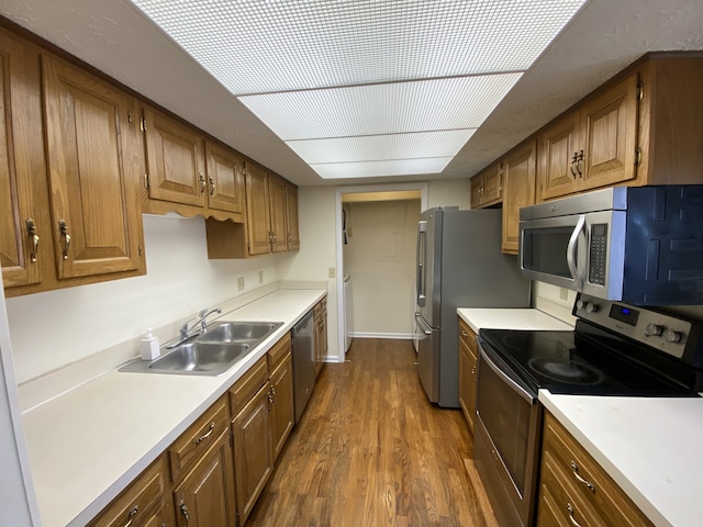 kitchen with appliances with stainless steel finishes, dark hardwood / wood-style flooring, and sink