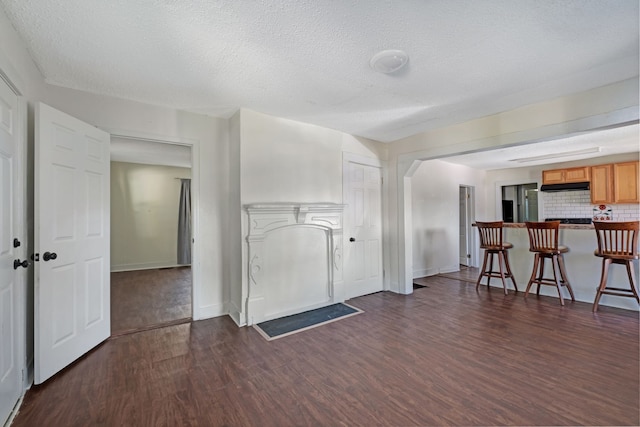 unfurnished living room with a textured ceiling and dark hardwood / wood-style floors