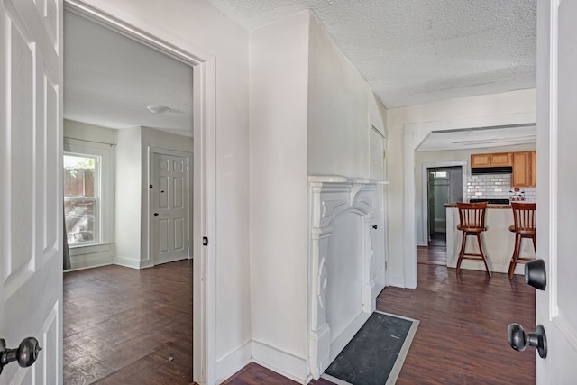 hall with dark wood-type flooring and a textured ceiling