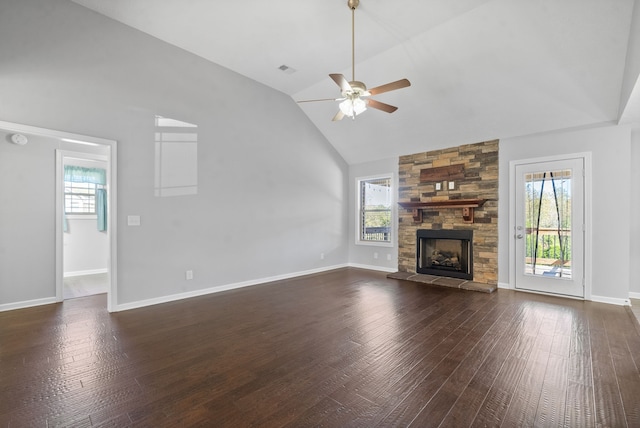 unfurnished living room featuring a wealth of natural light, vaulted ceiling, a stone fireplace, and dark hardwood / wood-style flooring