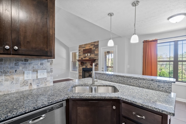 kitchen featuring dishwasher, sink, vaulted ceiling, light stone counters, and tasteful backsplash