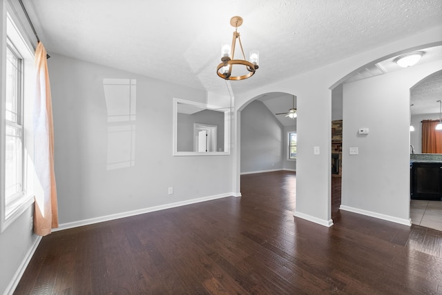 interior space with a textured ceiling, vaulted ceiling, dark hardwood / wood-style floors, and ceiling fan with notable chandelier