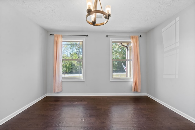 unfurnished room with a textured ceiling, a chandelier, and dark wood-type flooring