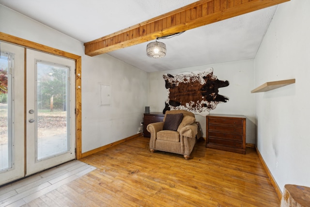 living area featuring vaulted ceiling with beams and light wood-type flooring