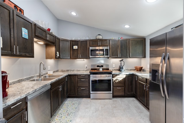 kitchen with lofted ceiling, light stone countertops, sink, dark brown cabinetry, and stainless steel appliances