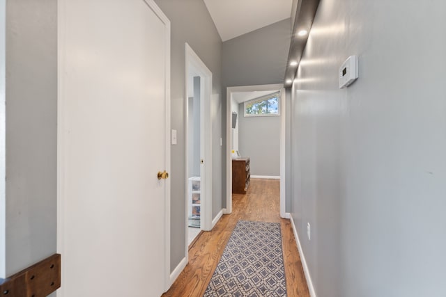 hallway with vaulted ceiling and light hardwood / wood-style floors