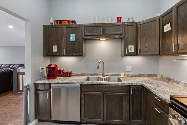 kitchen featuring light stone countertops, wood-type flooring, sink, dark brown cabinetry, and stainless steel dishwasher