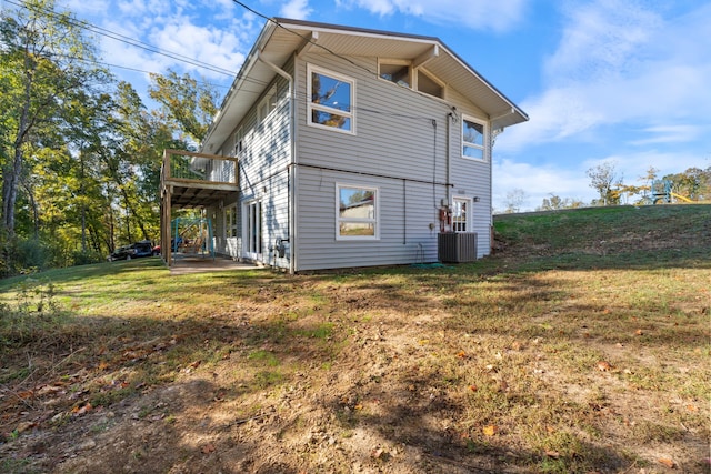 rear view of property featuring central AC and a lawn