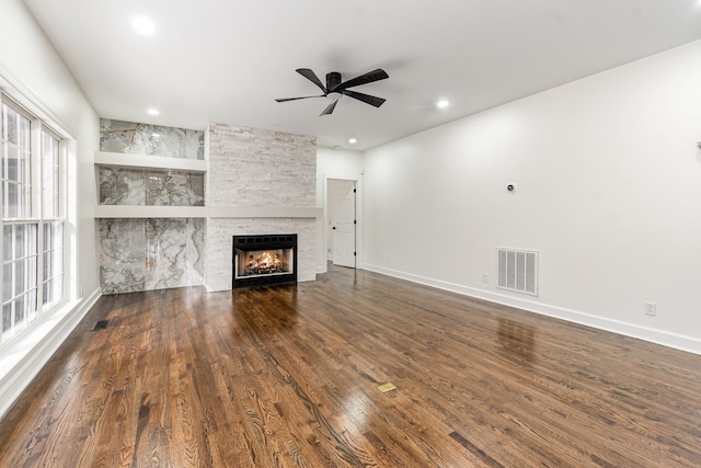 unfurnished living room featuring a fireplace, dark hardwood / wood-style floors, and ceiling fan