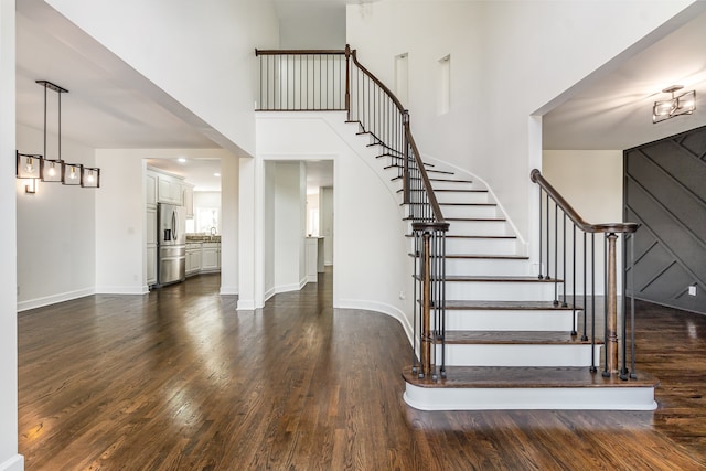 staircase with wood-type flooring, sink, and a high ceiling