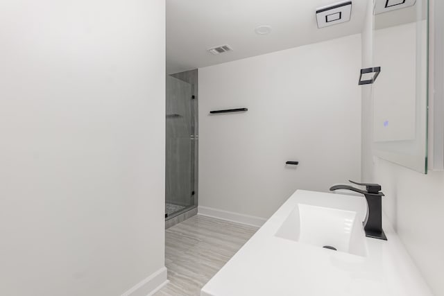 bathroom with hardwood / wood-style floors, vanity, and a shower with door