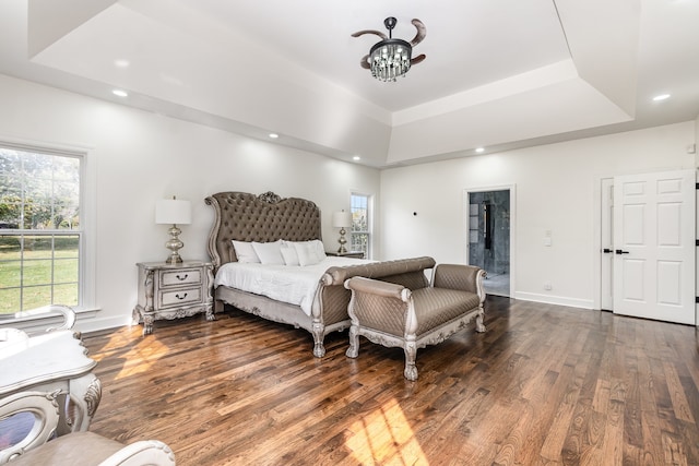 bedroom featuring a chandelier, dark hardwood / wood-style floors, and a raised ceiling