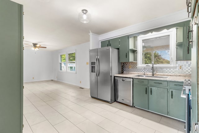 kitchen featuring tasteful backsplash, stainless steel appliances, ceiling fan, sink, and green cabinetry