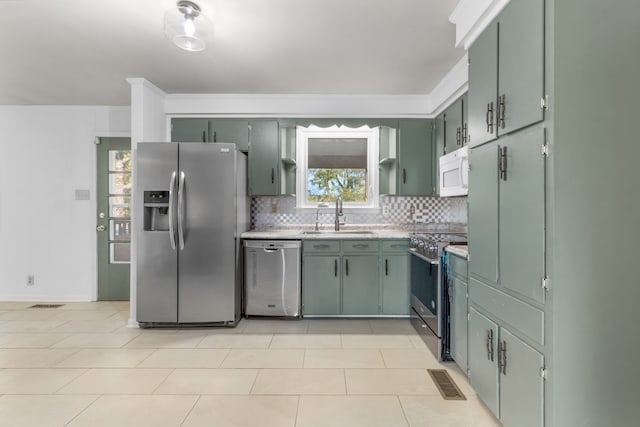 kitchen featuring tasteful backsplash, stainless steel appliances, sink, light tile patterned floors, and green cabinets