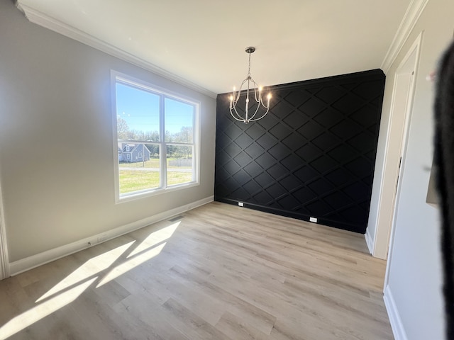 unfurnished dining area featuring crown molding, light hardwood / wood-style flooring, and a notable chandelier