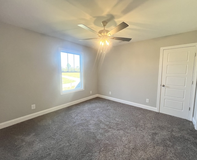 spare room with ceiling fan and dark carpet