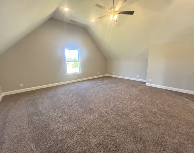 additional living space with ceiling fan, dark colored carpet, and vaulted ceiling