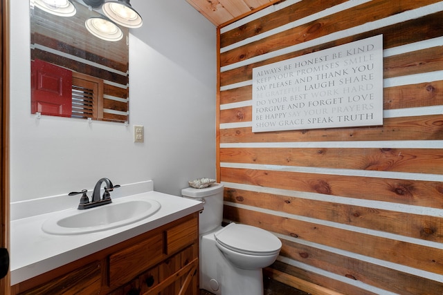 bathroom featuring vanity, toilet, and wood walls